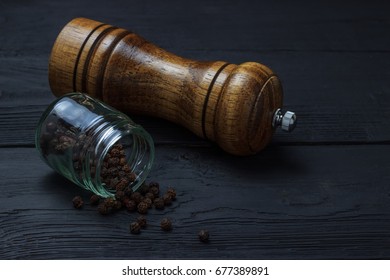 Jar With Black Pepper And A Mill On A Black Wooden Background