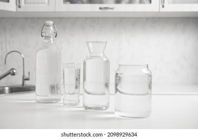 jar, bottle of water with full  transparent glasses on white table. kitchen interior. Pure drinking water. Clear aqua.