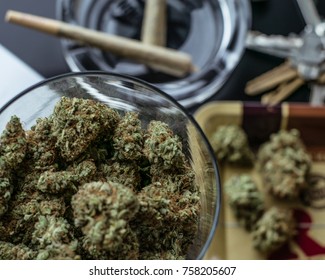 A jar of cannabis buds with related cannabis products on the tabletop background.