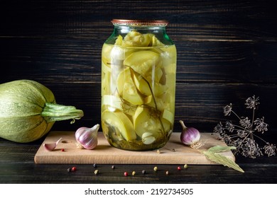 Jar with canned zucchini or vegetable marrow and spices on a wooden board after cooking. Place for an inscription or advertising.