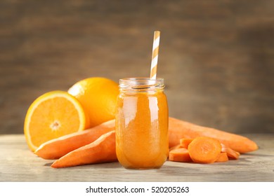 Jar with carrot and orange smoothie on wooden table