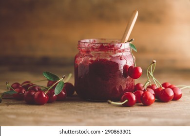 Jar of cherry jam, sour cherries and spoon