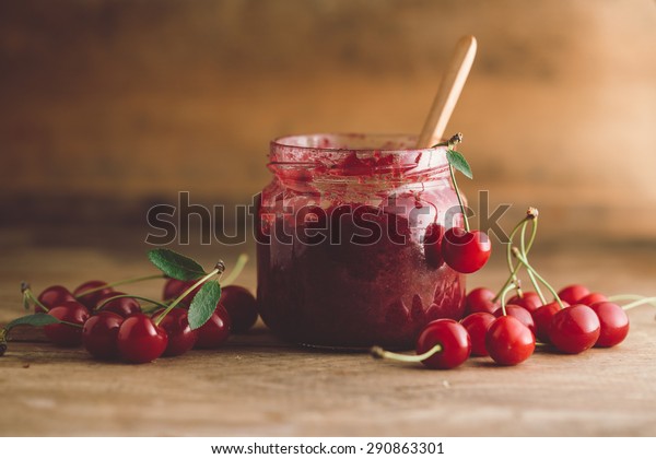 Jar of cherry jam,\
sour cherries and spoon