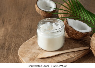 Jar of coconut butter and fresh coconuts with palm leaf on wooden background. Healthy vegan food. - Shutterstock ID 1928159660