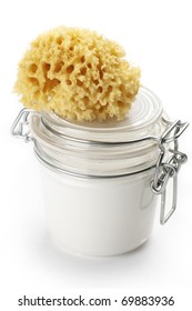 Jar of cosmetic cream and bath sponge isolated on white background.
