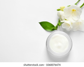 Jar of cream and flowers on white background, top view. Professional cosmetic products