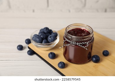 Jar of delicious blueberry jam and fresh berries on white wooden table - Shutterstock ID 2258579545