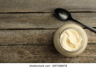 Jar of delicious mayonnaise and spoon on wooden table, flat lay. Space for text