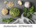 Jar of delicious pesto sauce and ingredients on grey table, flat lay