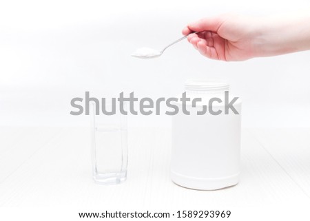 jar and glass of water on a white background, a hand holds a spoon and pours powder into a glass of water, absorbent treatment concept