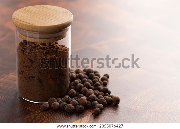 Jar of Ground and Whole Allspice on a Dark Wooden\
Kitchen Counter