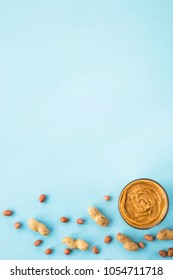 A jar of hazelnut paste among peanuts in shell and without on a blue background. Vegan product. American breakfast. Top view, Flat lay, Copyspace