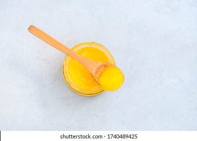 Jar of healthy ghee butter with spoon on neutral background with space for text
