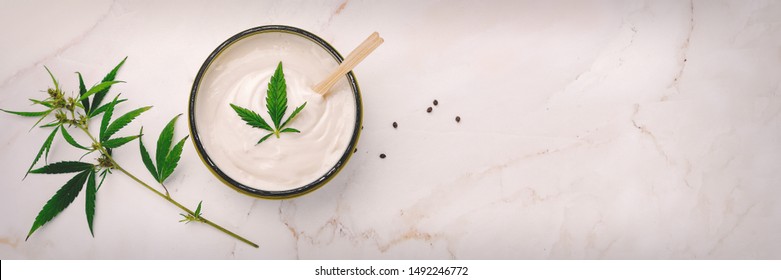 Jar of hemp white lotion. Cannabis cream with marijuana leaf - cannabis concept. Flat lay, top view.