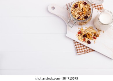 Jar of homemade muesli with nuts, berries, dried fruits,milk and honey on white background.Healthy breakfast. Top view