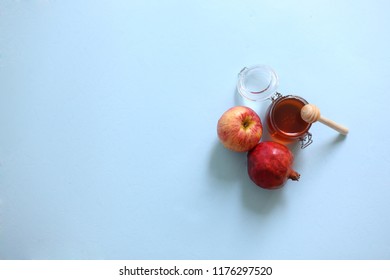 jar of honey, red pomegranate, red apple from top view symbols from Jewish holiday Rosh Hashana on blue background. - Powered by Shutterstock