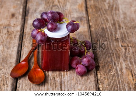 Jar of  jam and grapes on a wooden background. Delicious dessert.