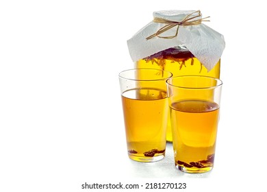 Jar Of Kombucha And Two Glasses Of Kombucha With Raisins Isolated On A White Background On A Light Gray Concrete Table. Low Alcohol Carbonated Drink On A Hot Day