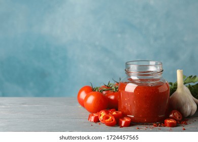 Jar with red chilli and tomato sauce, and spices on wooden table - Powered by Shutterstock