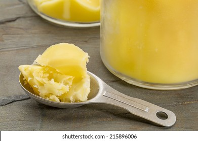 jar sand measuring tablespoon of ghee - clarified butter on grunge wood