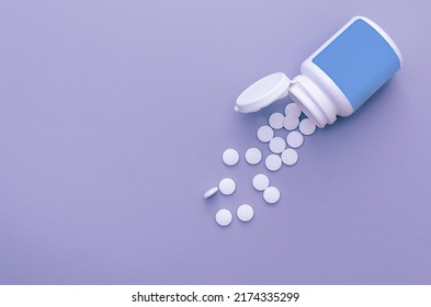 A Jar And Scattered White Pills On A Blue Background. Medicine, Health, Vitamins, Drug Manufacturing. Free Space For Text.