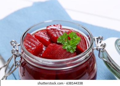 jar of sliced and pickled beetroot on blue place mat - close up
