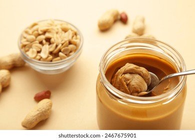 Jar and spoon of peanut butter on beige background. Top view - Powered by Shutterstock