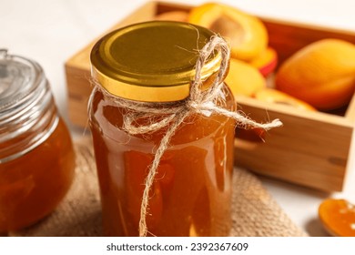 Jar with sweet apricot jam on white background