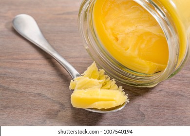 jar and  tablespoon of ghee (clarified butter) on grunge wood