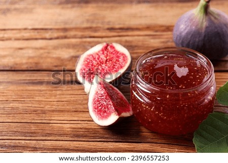 Jar of tasty sweet jam and fresh figs on wooden table, closeup. Space for text