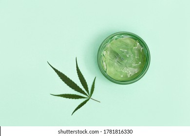 Jar With Transparent Cosmetic Product, Gel Or Cream With Cannabis Oil On Blue Colored Background. Flack With Of Antioxidant Cream For Self-care. View From Above.