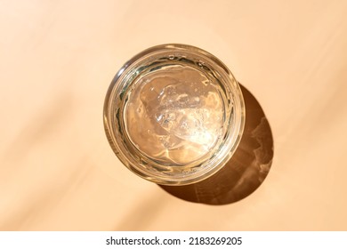 Jar With Transparent Cosmetic Product, Gel Or Cream On Beige Colored Background. Unbranded Package With Of Antioxidant Cream For Self-care. View From Above.