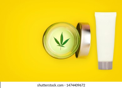 Jar And Tube With CBD Cannabis Gel And Lotion On Yellow Background