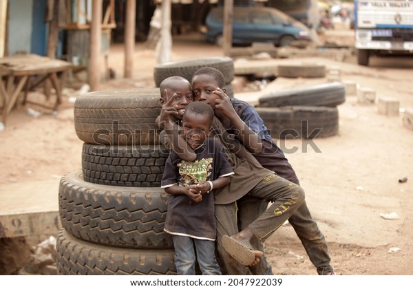 Jarra Soma, the\
Gambia, Africa, June 20, 2021, photography of small african boys in\
dark clothes, posing in front of a pile of used black tires,\
outdoors on a sunny day