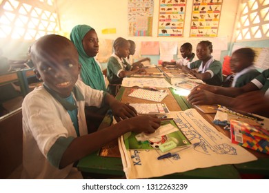 Jarra Soma Region, The Gambia, Africa; March 17, 2017: Horizontal Closeup Of  Elementary School Students In White And Green Uniforms, Sitting By Vintage Desks, On Sunny Day