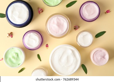Jars of body cream on color background