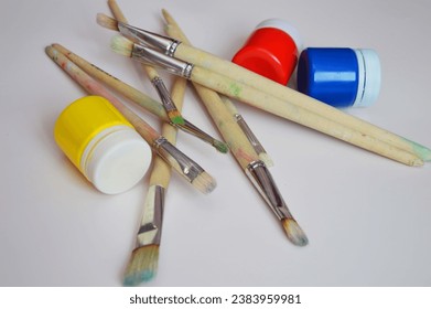 Jars with bright gouache paints and artistic bristle brushes of different sizes. Materials for hobbies, drawing and creativity. - Powered by Shutterstock