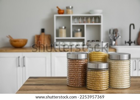 Jars with cereals on wooden table in kitchen