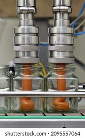 Jars of creamed honey being filled in a packaging line at a commercial honey factory