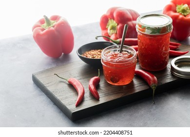 Jars Of Delicious Red Pepper Jelly Against A Bright Sunny Window.