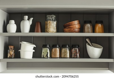 Jars with different spices and kitchen utensils on shelves - Powered by Shutterstock