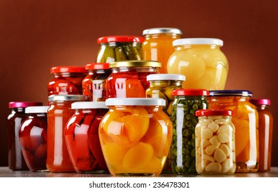 Jars with fruity compotes jams and pickled vegetables. Preserved fruits
