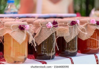 Jars Of Homemade Jams Prettily Hand Decorated With Roses And Hessian Displayed On A Craft Market Stall