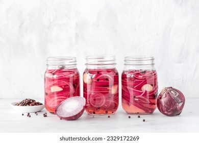 Jars of homemade pickled red onions with peppercorns.