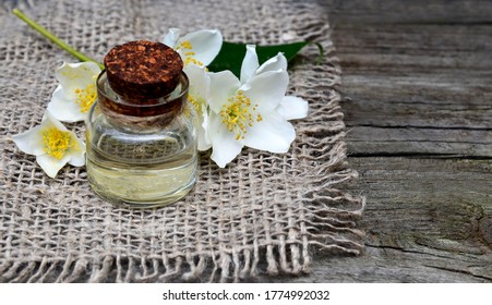 Jasminätherisches Öl in einer Glasflasche und frische Jasmin-Blumen auf altem Holzhintergrund.Aromatherapie, Spa oder Wellness Konzept.Selektiver Fokus.