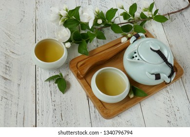 Jasmine Tea. Organic Tea With Jasmine Extract.green Teapot And Cups In Asian Style On A Wooden Tray And Sprigs Of White Jasmine On A Light Shabby Chic Wooden Background