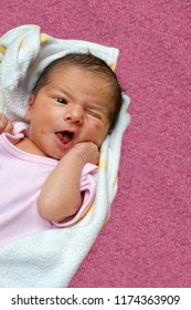 Jaundice Newborn Baby Laying On  Back, Exhibiting The Rooting Reflex As Her Hand Touches Her Cheek.  She Turns Her Face To The Side To Latch On.  She Has Flaky, Imperfect Skin And Her Eye Is Yellow.