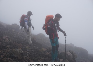 Java, Indonesia - October 21, 2021: Two Mountain Climbers Walk Through The Fog.