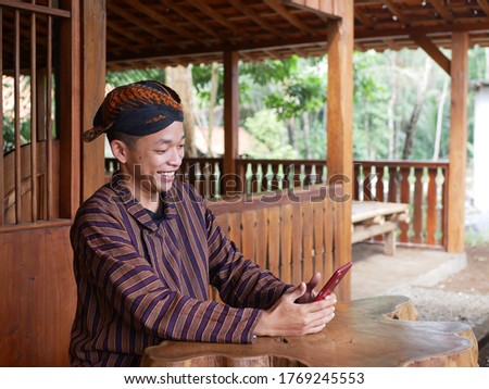 a javanese Man using a smartphone 