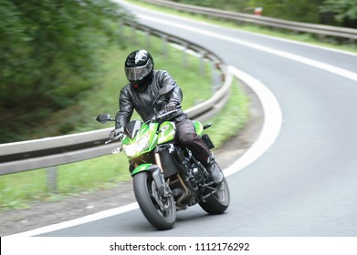 Jawor, Poland - April 2018: The driver of a green, sports motorcycle, wearing a complete safety suit, goes into a bend at high speed. The beginning of the motorcycle season is open.